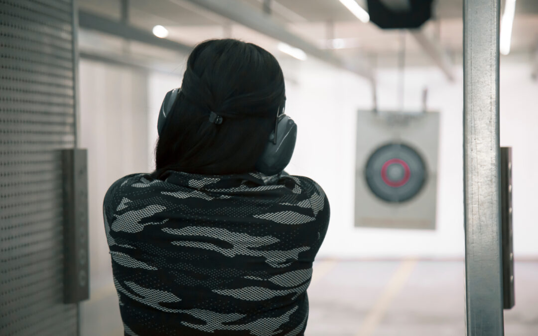 woman aiming pistol at a target in an indoor shooting range